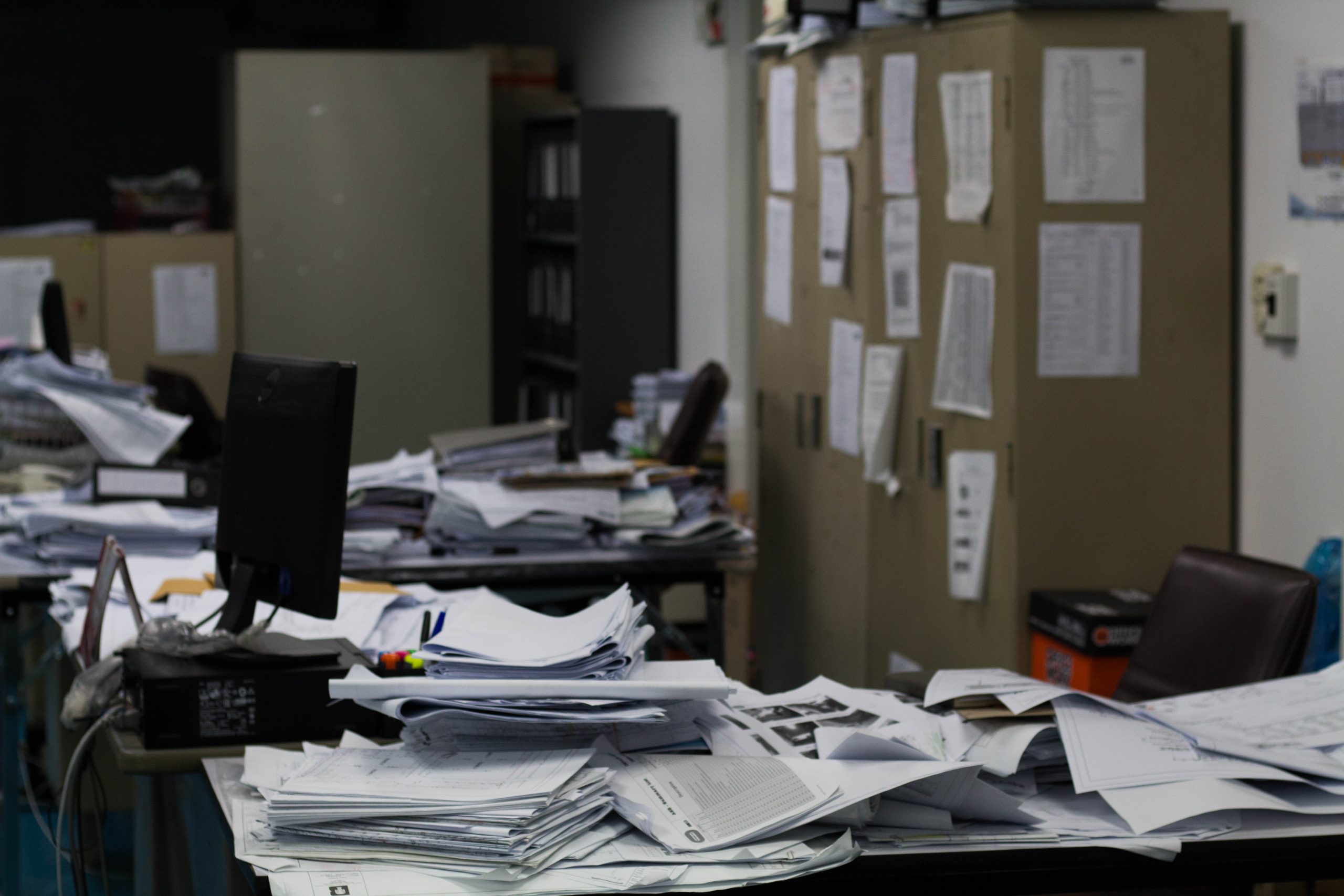 Messy and cluttered desk with documents in an office space, highlighting the need for professional office cleanout services.