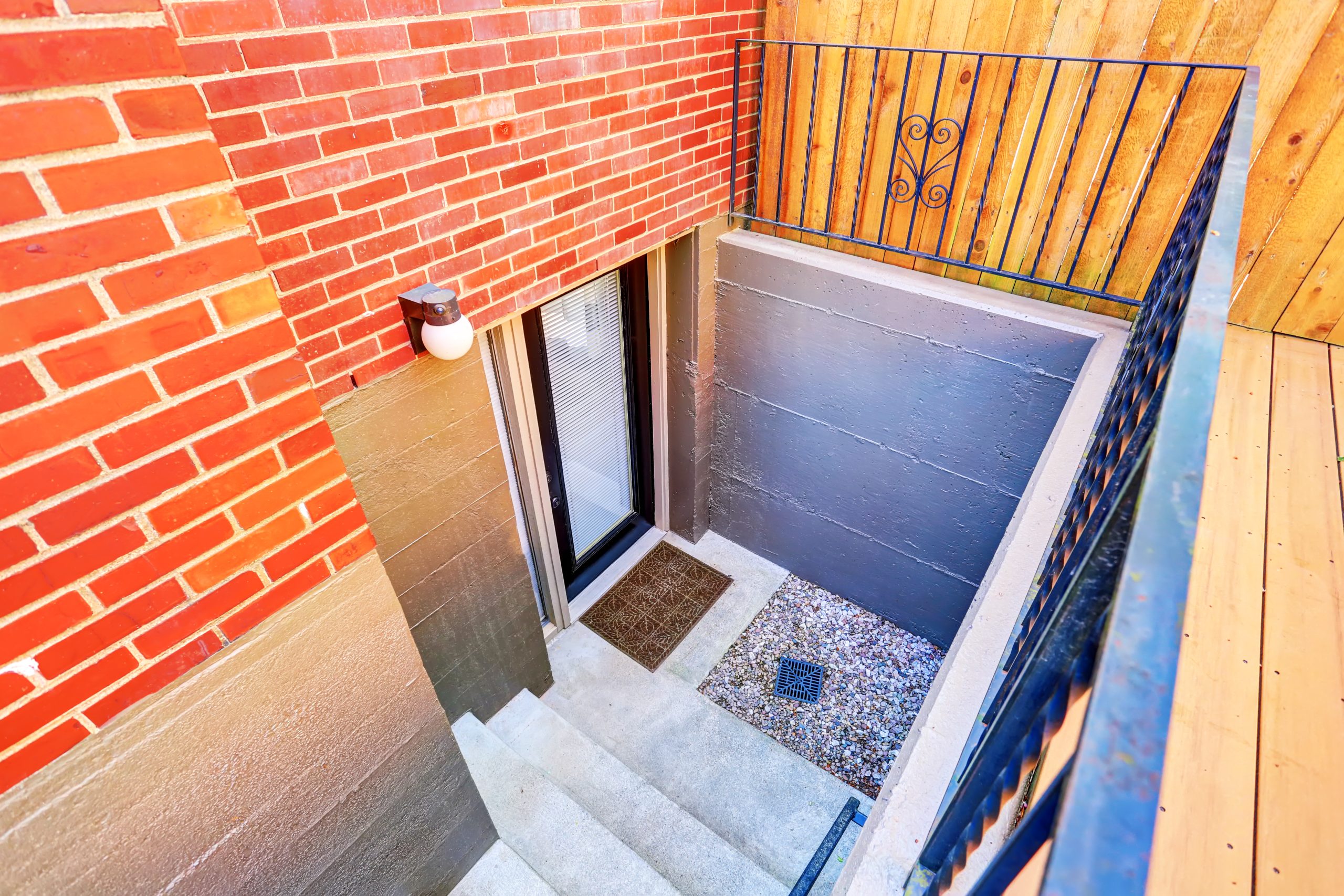 Exterior steps leading to the underground basement of a brick house, a common area needing property cleanout and junk removal services.