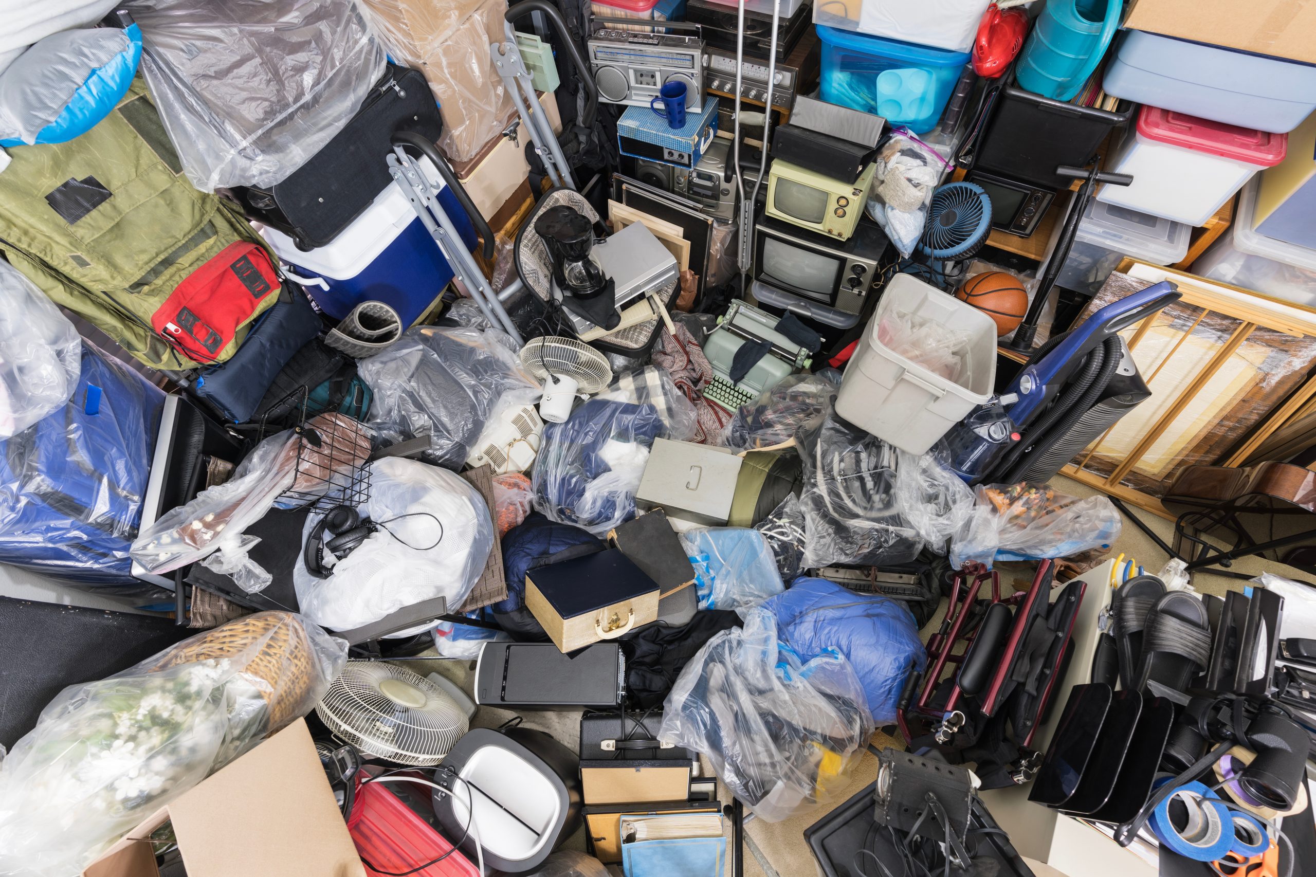 Hoarder room packed with boxes, electronics, business equipment, and household objects, illustrating the need for professional property cleanout services.