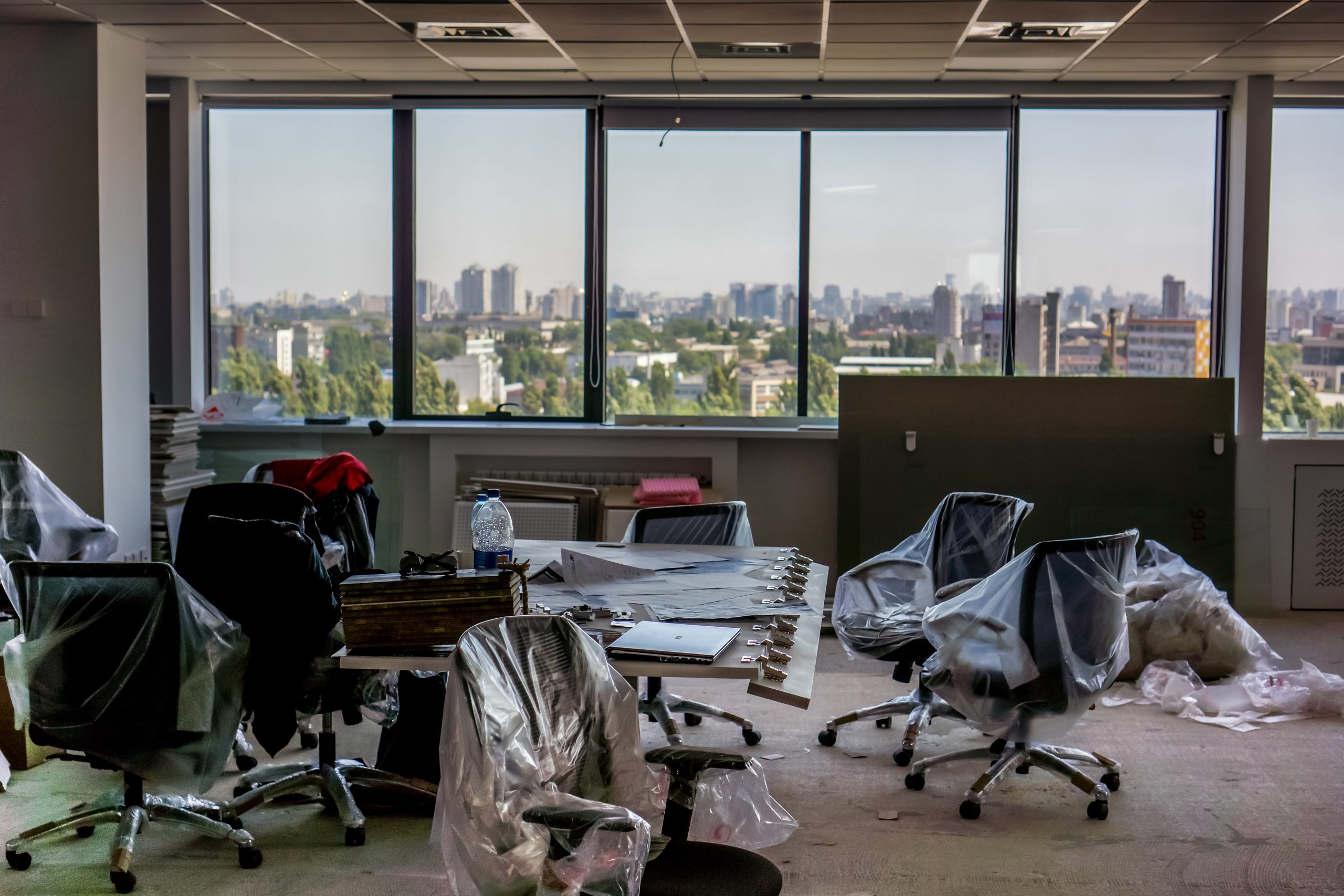 Black office armchairs packed into clear storage containers, illustrating an office space cleanout.