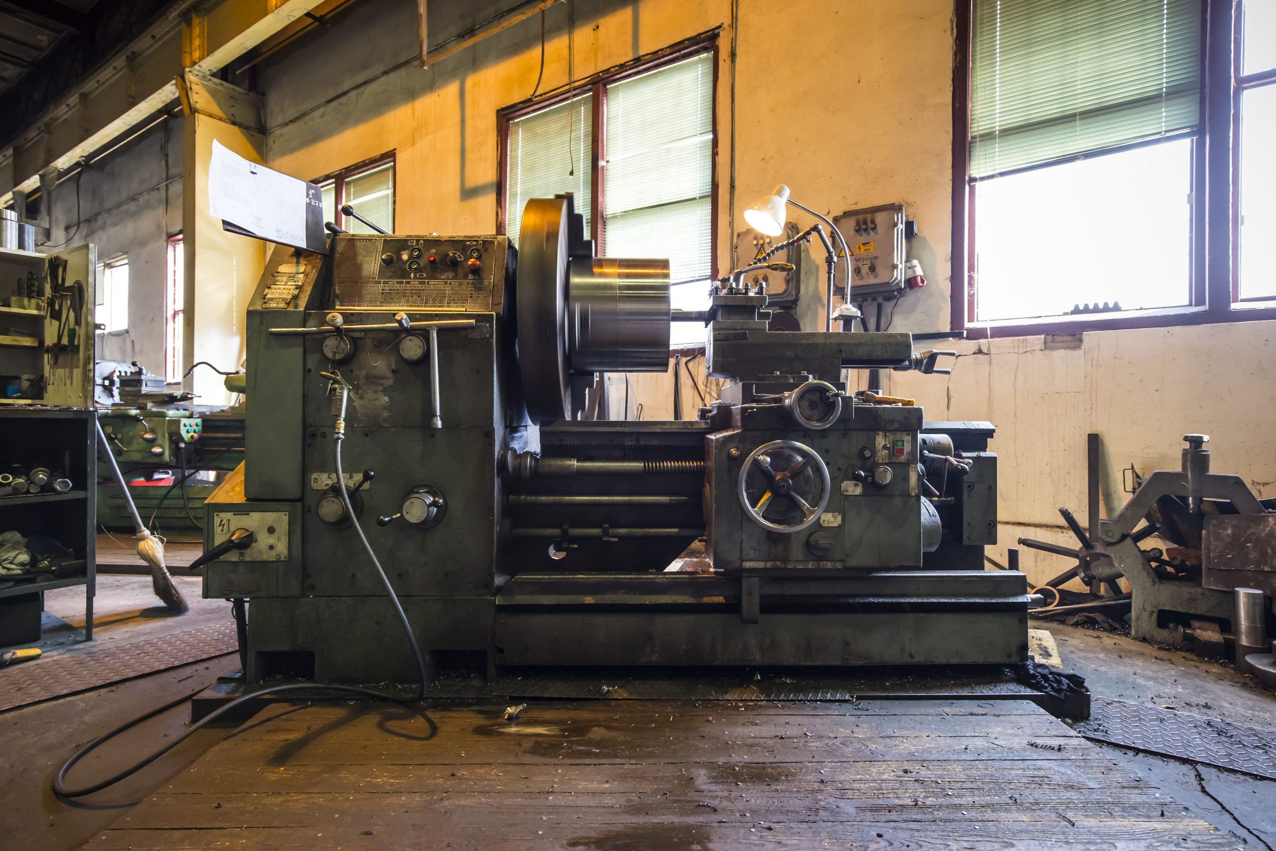 Old rotary lathe machine tool equipment in factory interior, highlighting the need for industrial cleanout services.