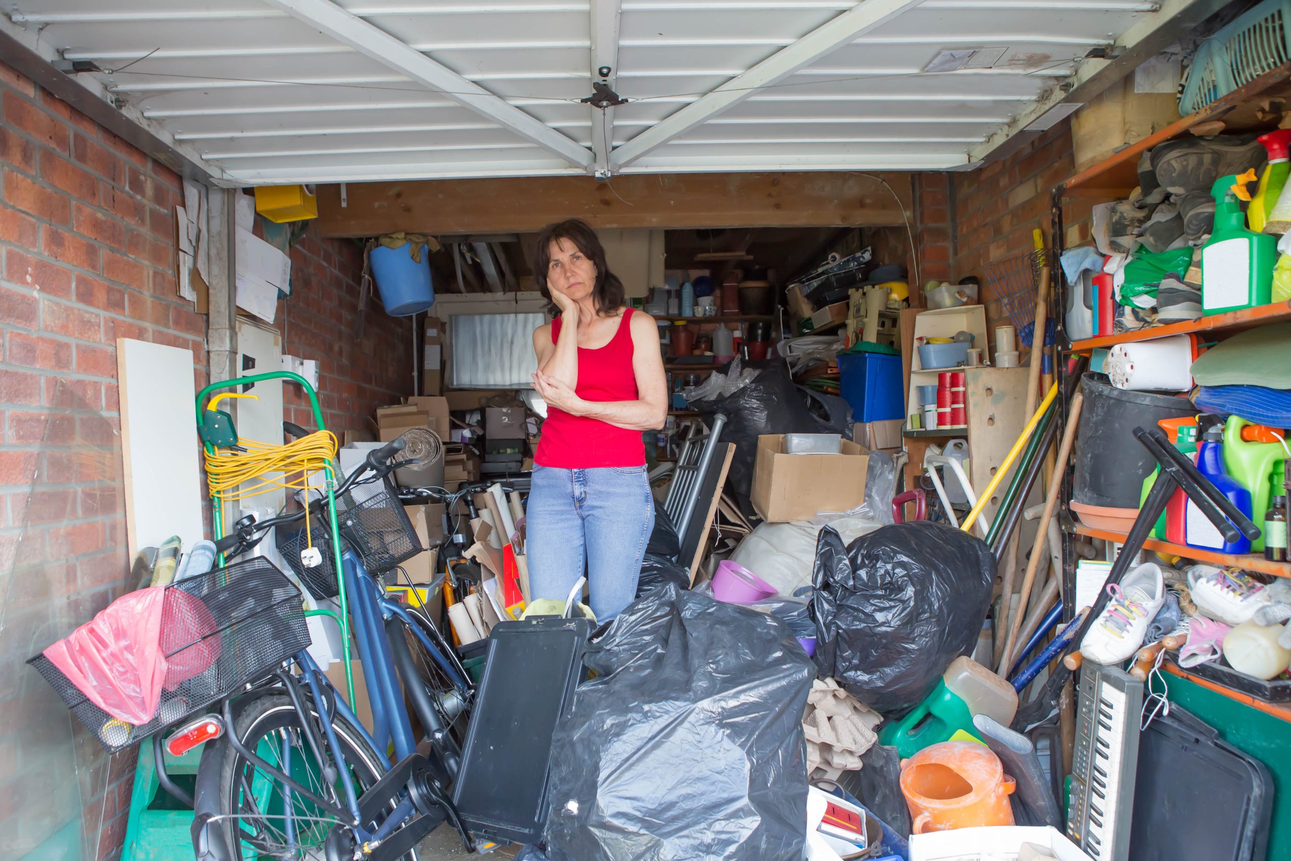 Woman looking bemused about where to start in clearing out a cluttered space, highlighting the need for professional property cleanout services